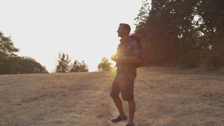 A man is looking at nature in a wooded area