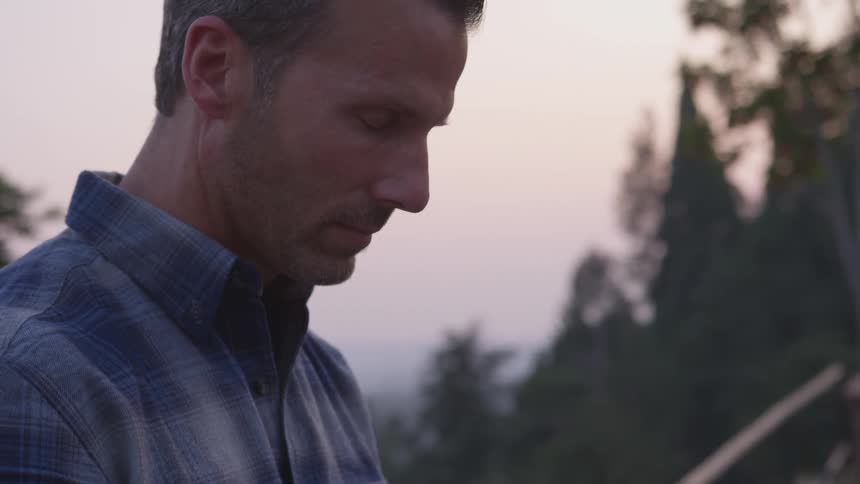 A man is closing his eyes outdoors