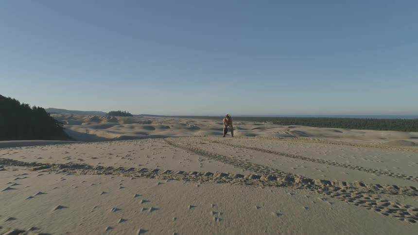 Man bends forward hands on his knees in desert in daytime