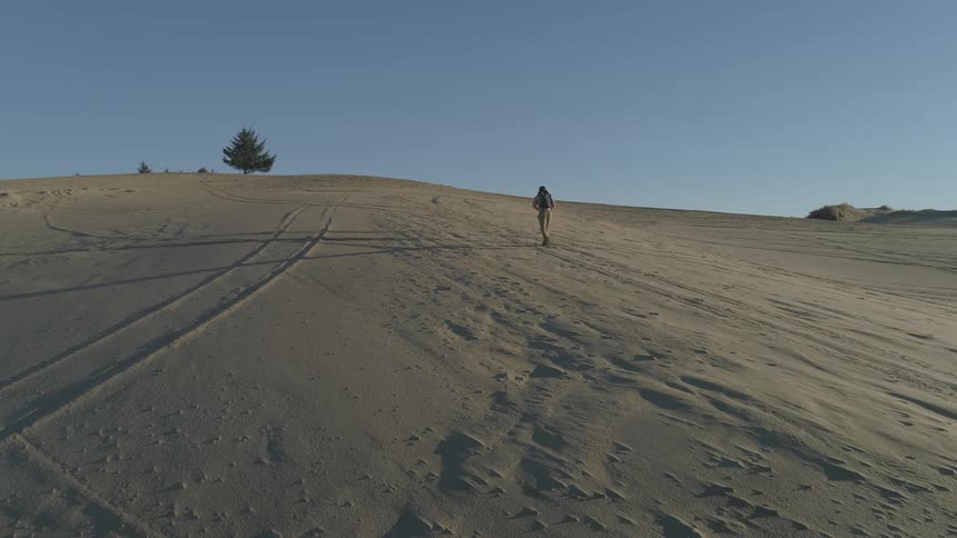 A man climbs a small hill in a desert on a clear day