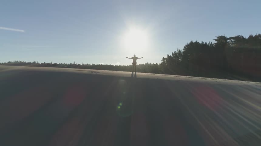 A man is spreading his arms wide on a cliff