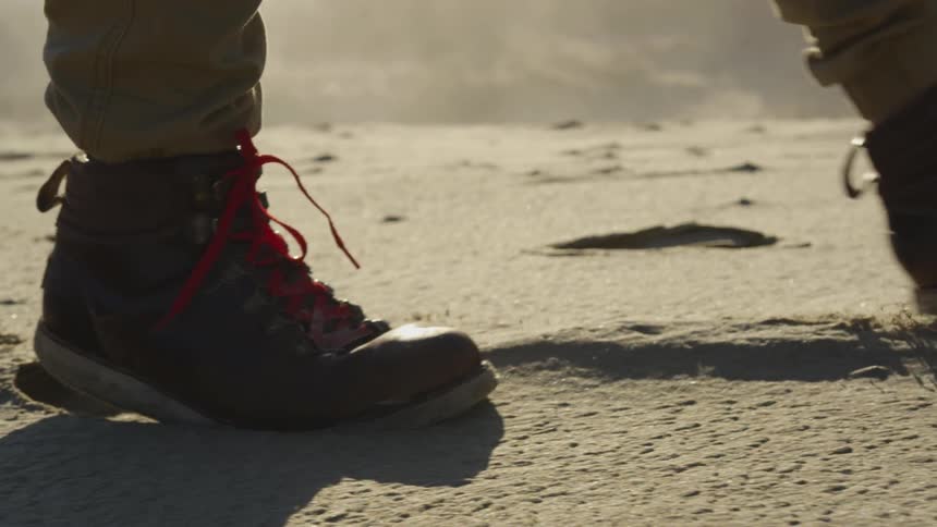 A man with boots on walking on a sandy valley