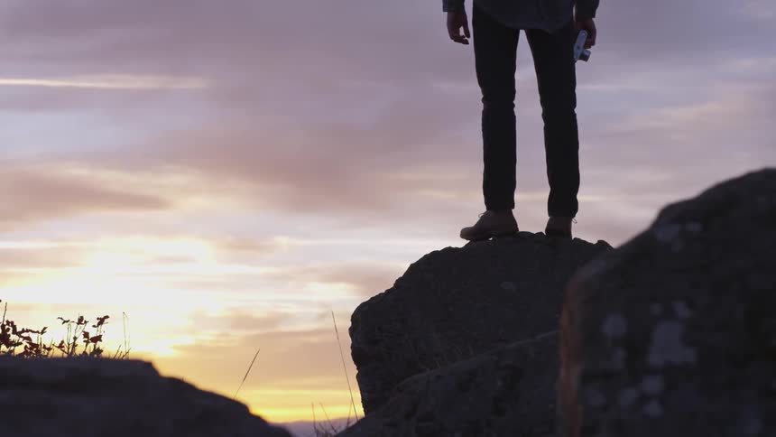 A man is standing on top of a rock