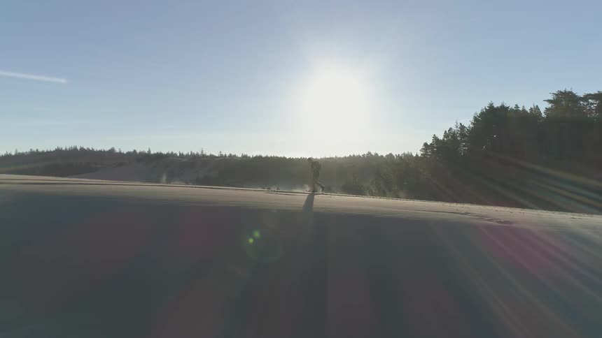 A man walks on the sandy edge of a dune at sunrise