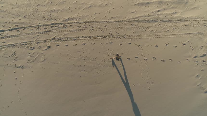 Overhead view of person walking on sand