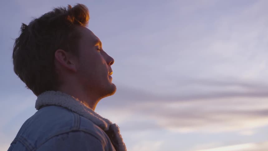 A young man relaxing outdoors while winds his hair