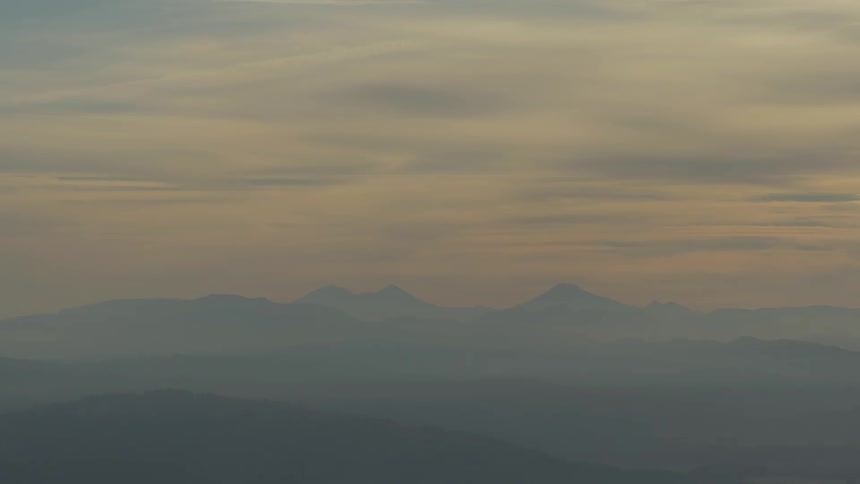 Clouds go over the mountains on a foggy day at dusk