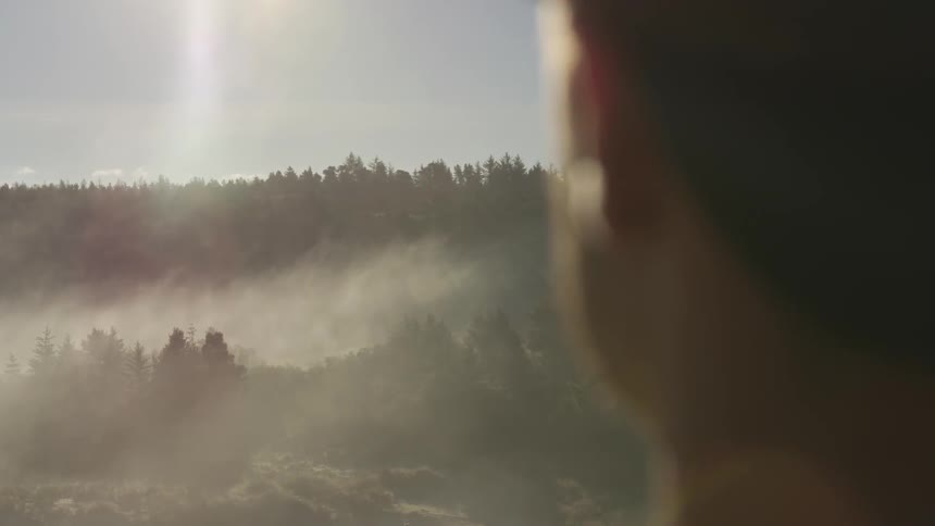 Man looks across foggy valley in daytime