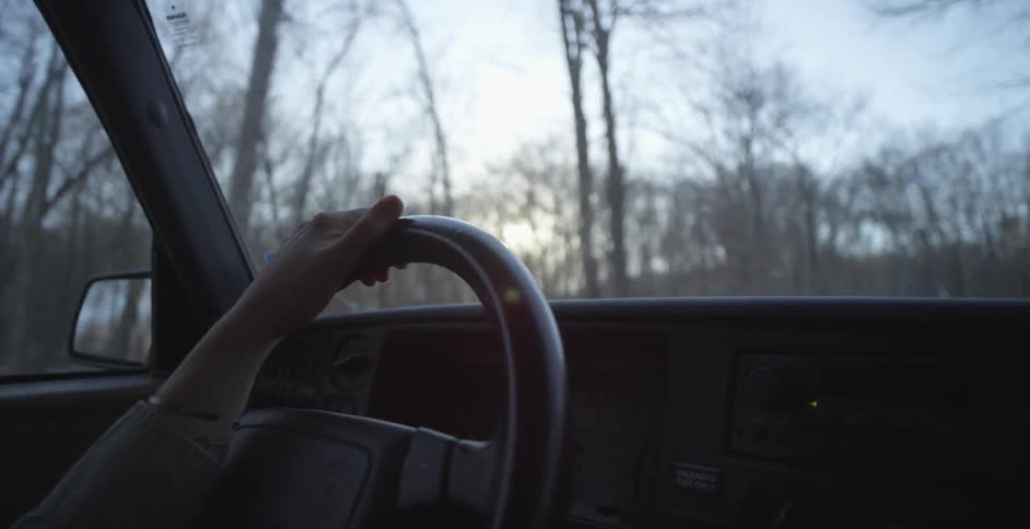 Woman drives through a forest road during the daytime