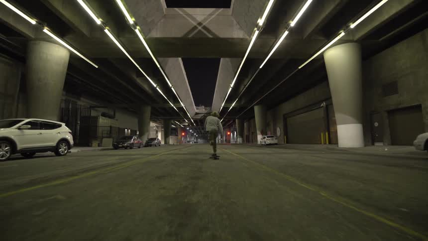 Young man skateboards under a bridge in a tunnel