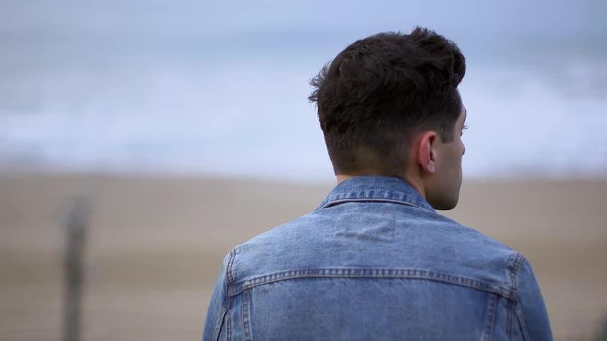 Man and jean jacket looking at something in a wide open area