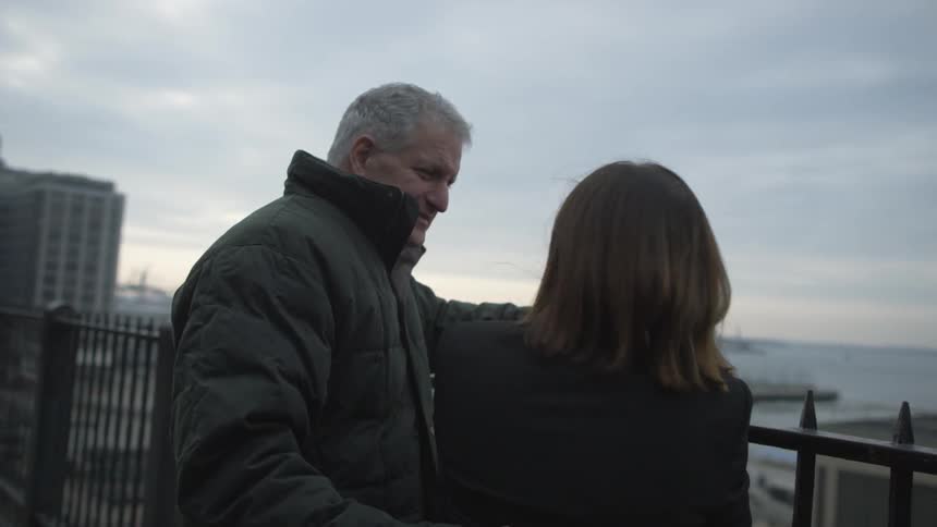 A man and woman standing next to an iron fence in the city