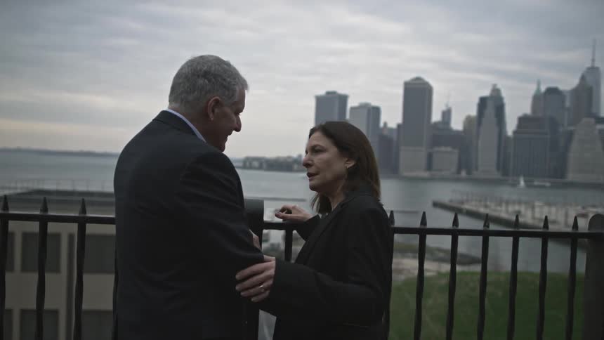 A man and woman stand with skyscrapers in the background