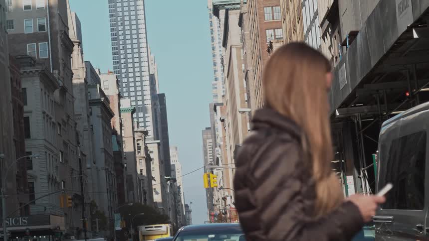 Woman crosses a busy city street while staring downwards at her phone