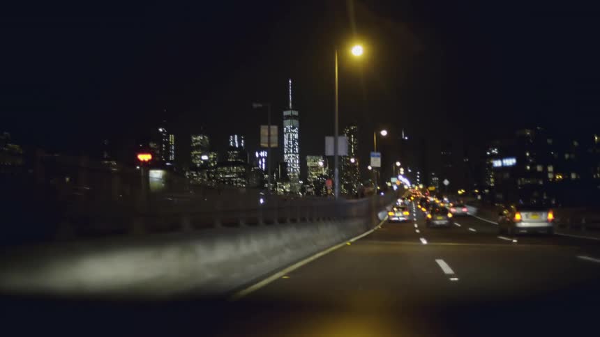 Many vehicles travel on a highway entering a city at night