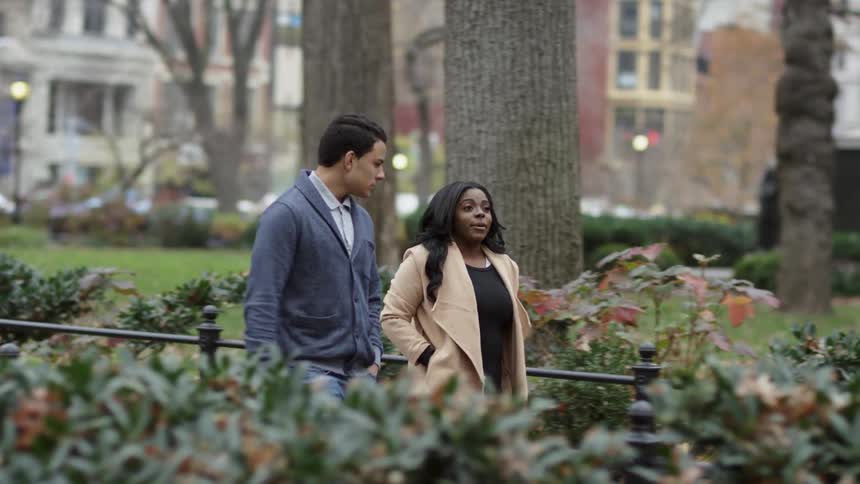 Couple walking down a walkway with bushes on both sides