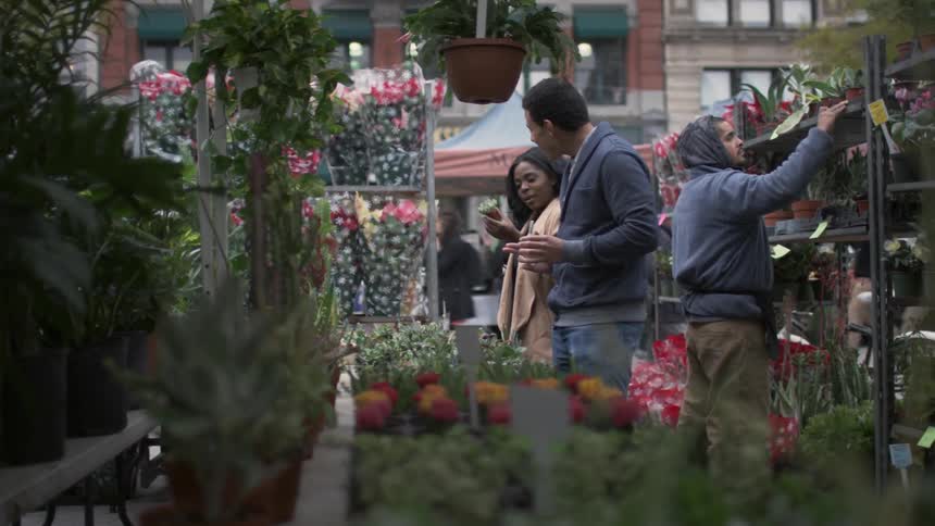 People standing in an outside florist examining flowers
