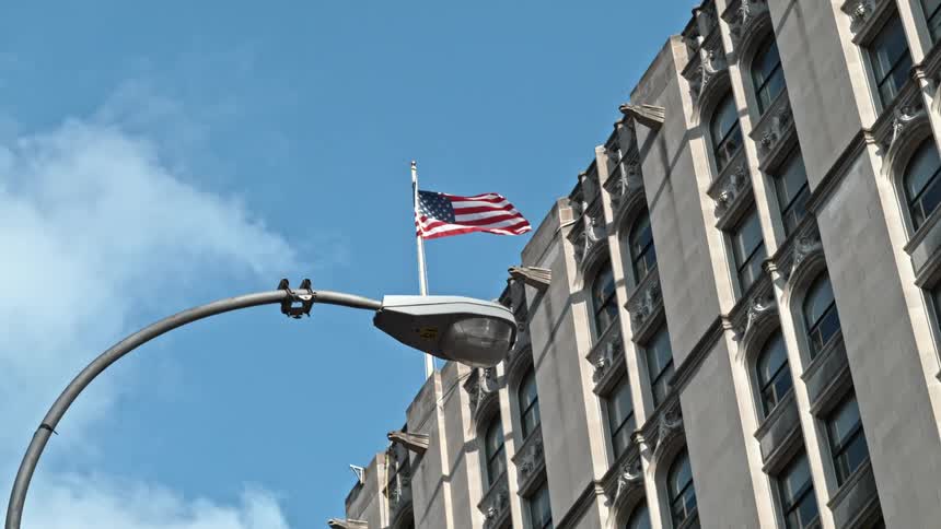 Flagpole with flag flying on top of multi-storied building