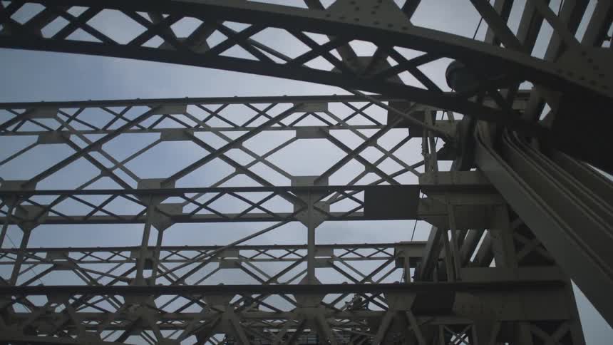 The trellis and support structure of a bridge against a blue sky