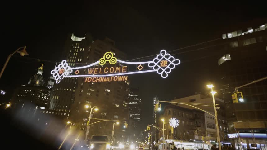 First person view of driving in an urban area and under a sign saying "welcome to chinatown"