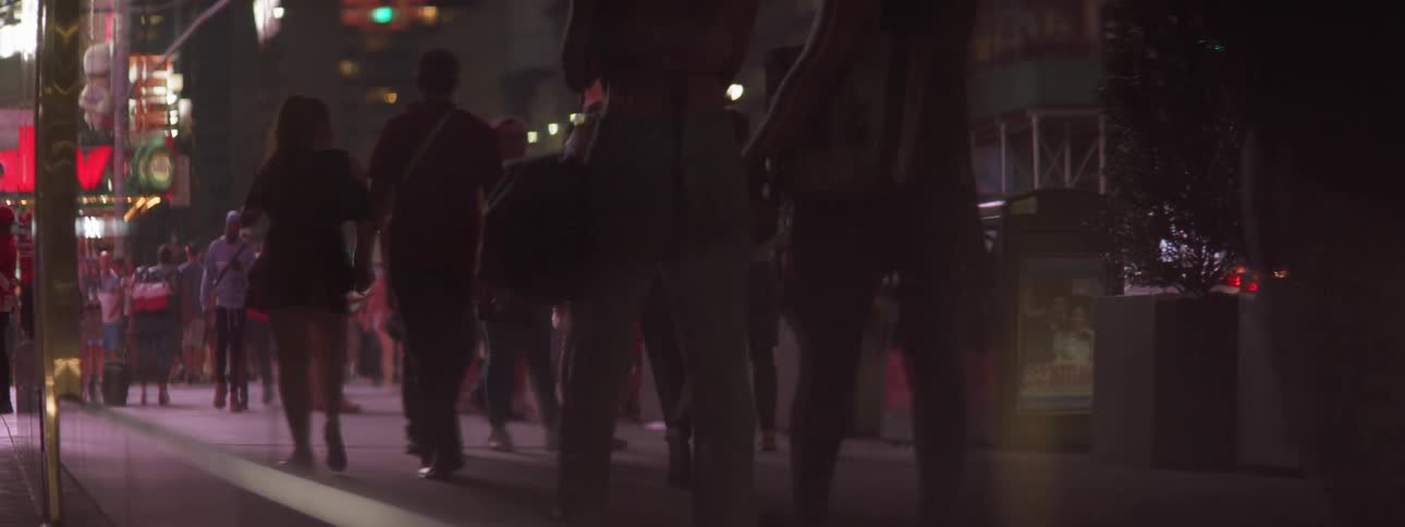 Pedestrians walking down sidewalk at night