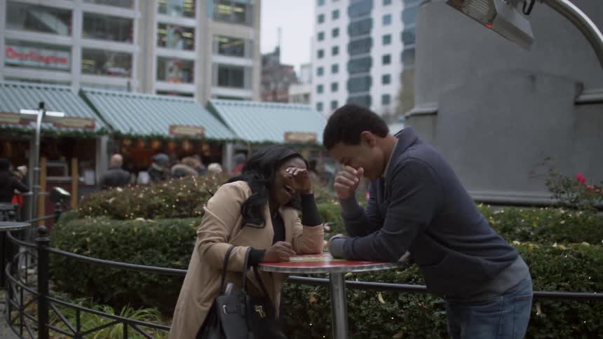 Man and woman sitting at a table laughing on a cloudy day