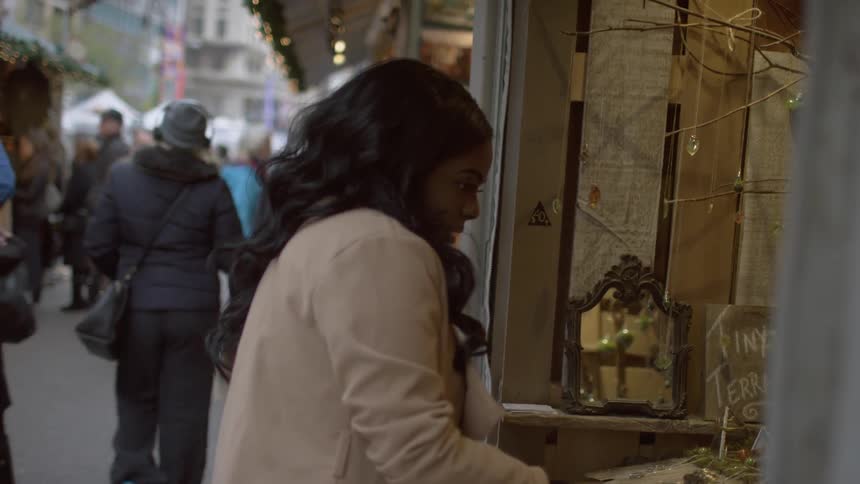 People walking all over a market as a woman examines items