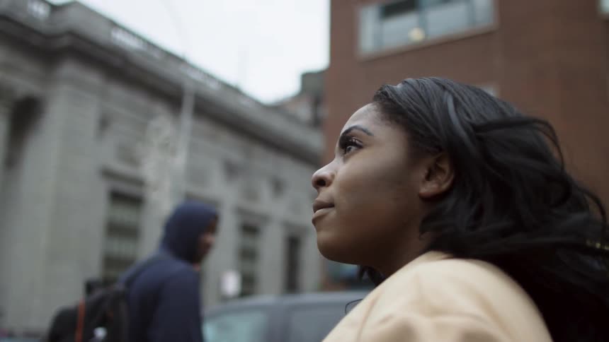 Woman standing on a busy city street looks around