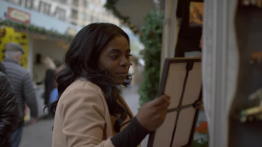 A woman examines a portrait at a sidewalk shop