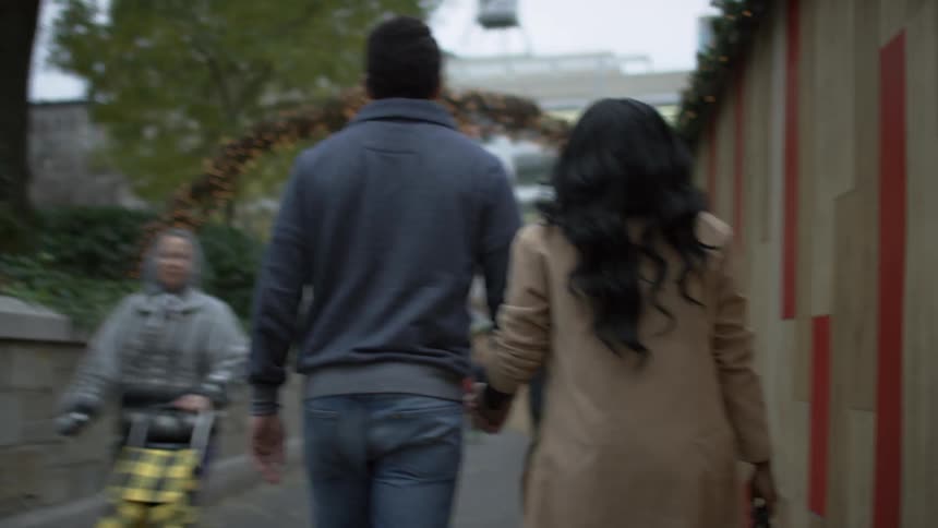 Man and woman hold hands as they walk down a road