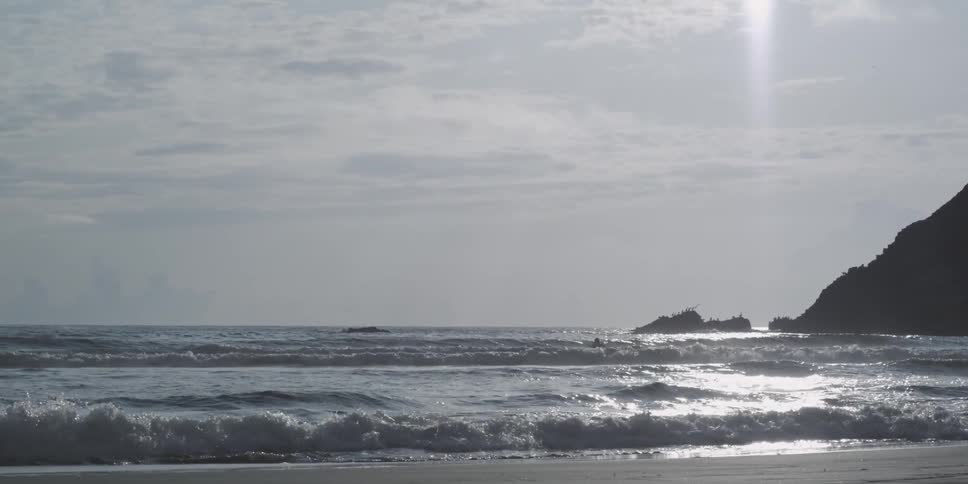 A lone surfer paddles his board out in search of a wave ride