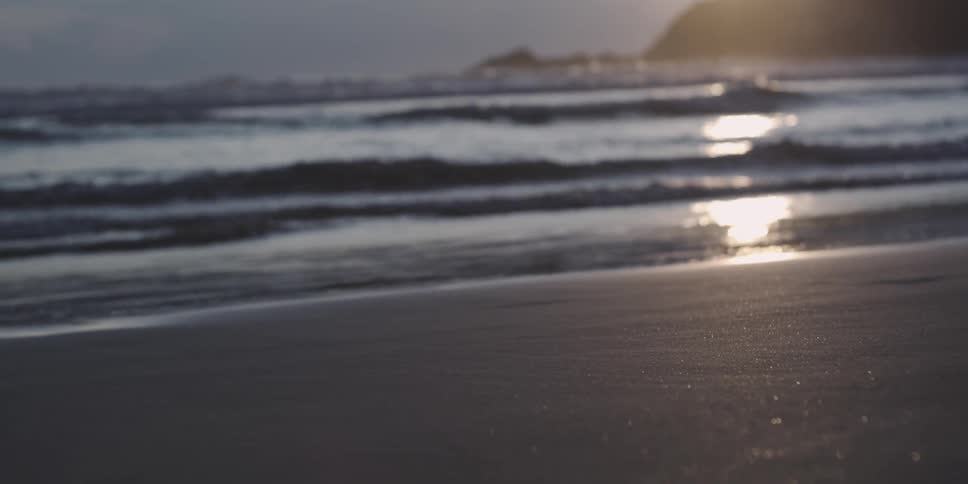 A beach with waves crashing at sunset