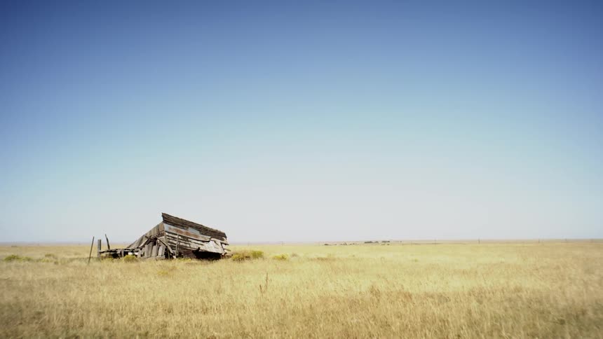 An abandoned structure in the middle of a vast field