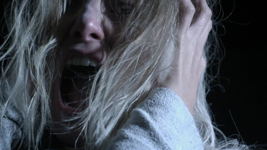 A woman holds her head and turns in a dark room