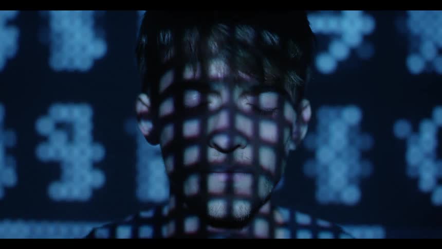 Monitor lights up the face of a man as he blinks