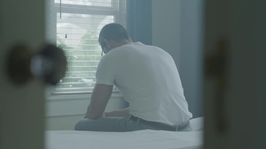 Man Sitting And Thinking On Bed