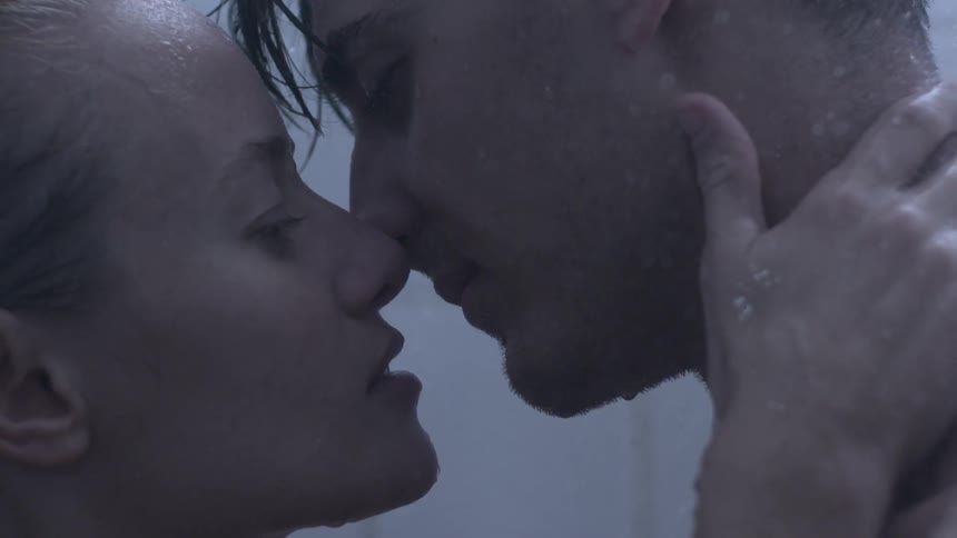 Man and woman kiss as water pours on them