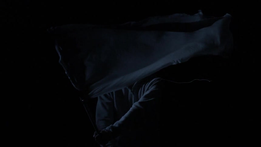 A man waves a white flag in a dark area