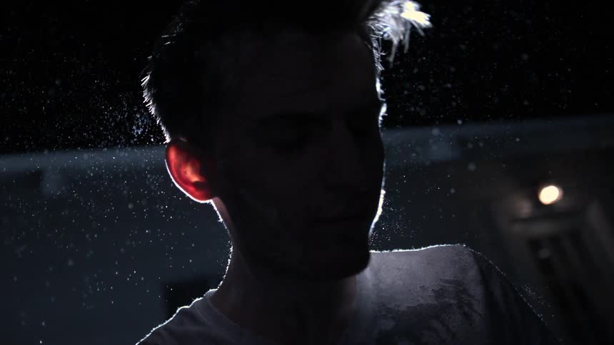 Man tossing his head in a dark area