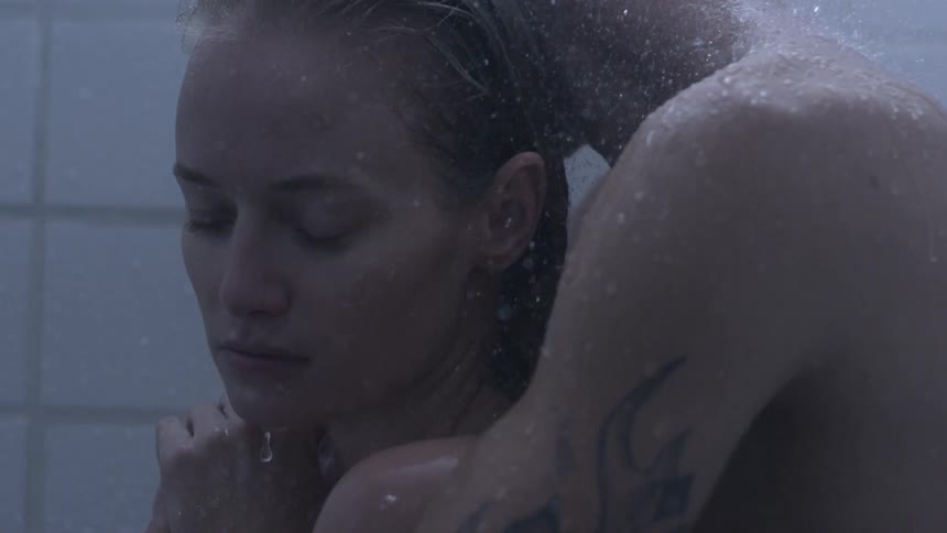 A man holding a woman as they stand in a shower