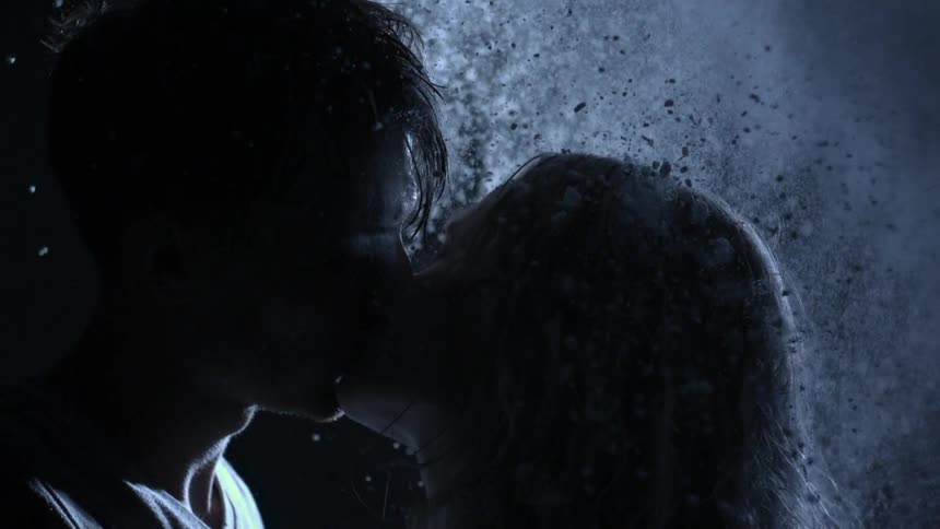 Man and woman kiss as something falls around them