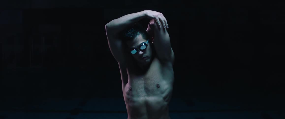 Man wearing goggles stretching in a dark area