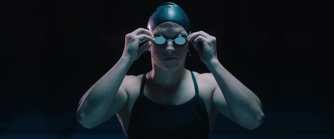 A woman swimmer fastens her goggles and crosses her arms