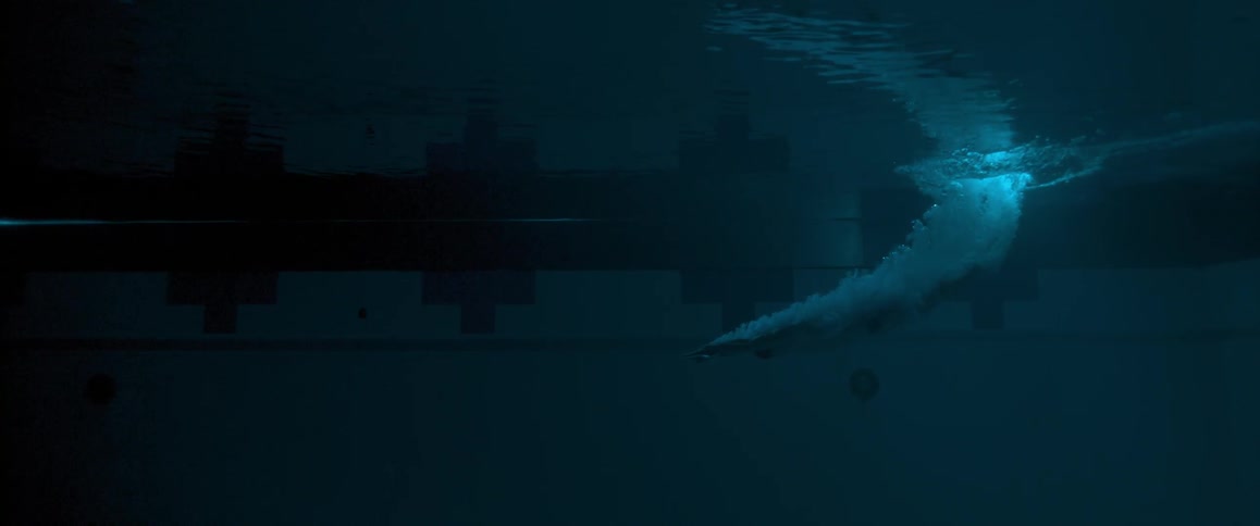 A dark underwater view of a man diving into water