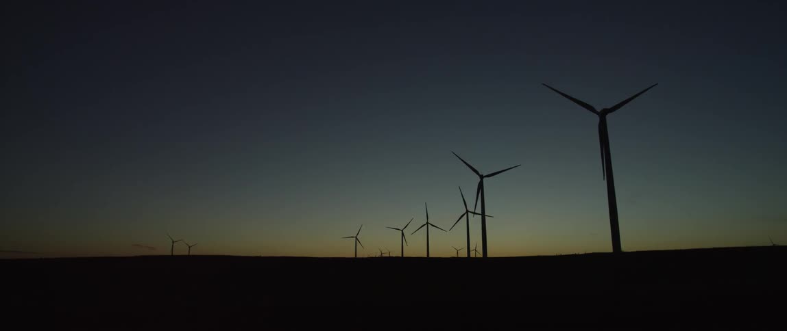 Wind turbines run as the sun sets