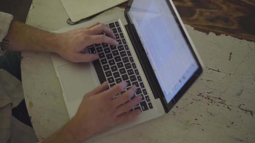Man Working On Computer At Kitchen Table