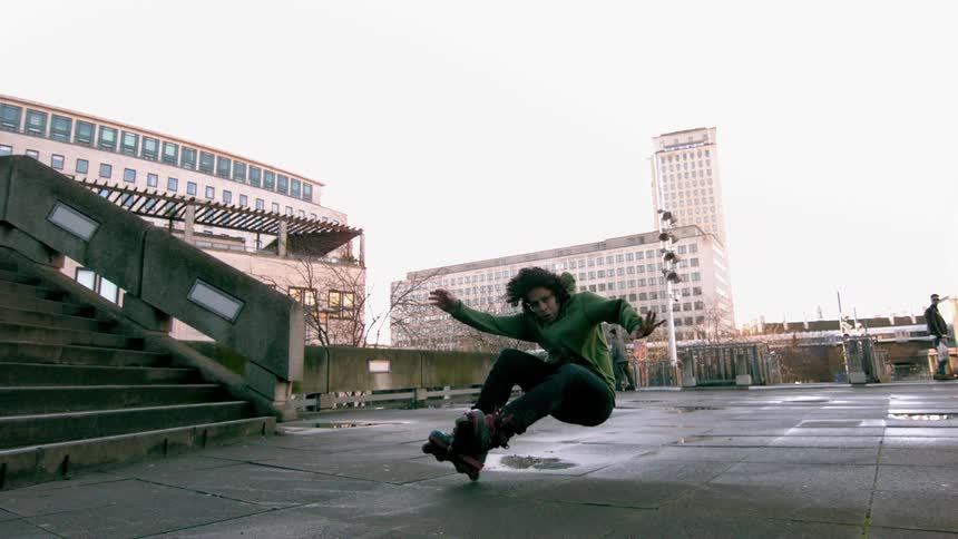 Person jumping stairs and landing backwards while falling wearing rollerblades at a city park