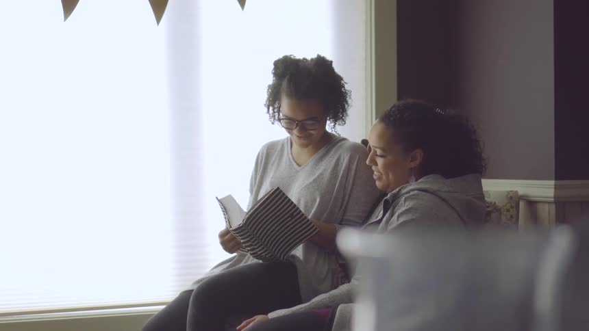 Mom And Daughter Talk In A Living Room