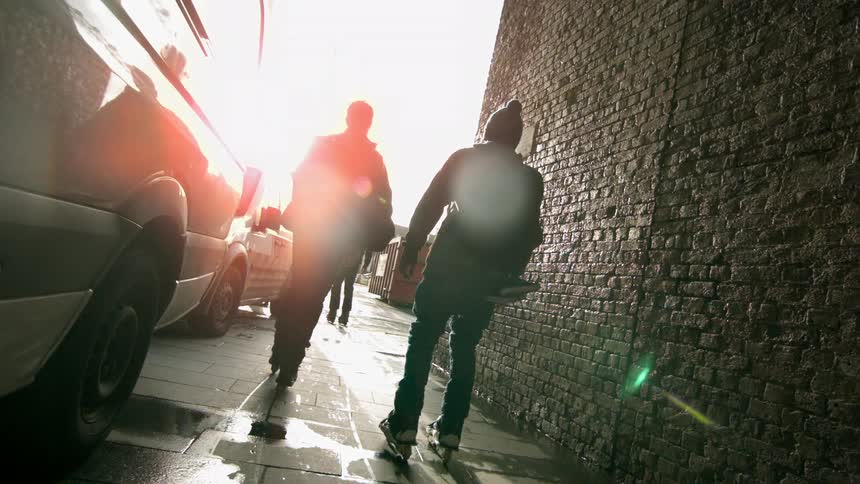 Men rollerblading in a city at sunset