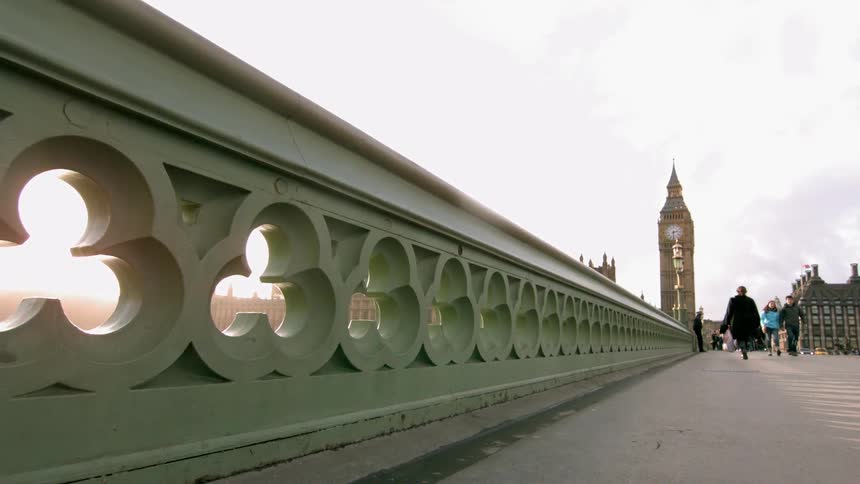 Super slow motion of people walking over a bridge with big ben in the background